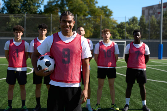 Diverse men's soccer team posing on training field - Powered by Adobe
