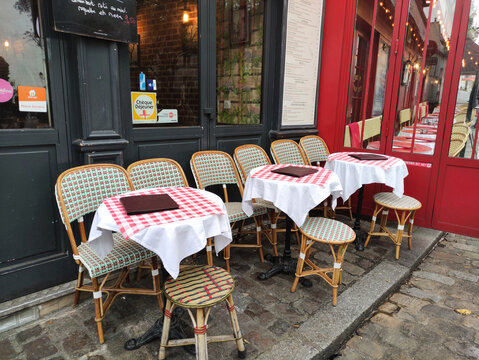 Paris, France - November 22, 2025: Outdoor cafe scene featuring empty tables with checkered tablecloths and chairs, inviting ambiance for dining in a charming Parisian setting