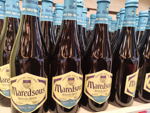 Brussels, Belgium - November 24, 2025: Bottles of Maredsous Triple Tripel beer arranged neatly on a shelf, showcasing the distinct label design and vibrant blue caps in a retail environment