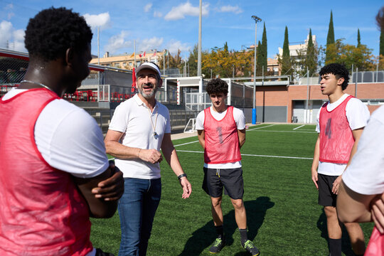 Soccer coach instructing diverse team players on field