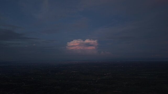 Aerial view of the soft, pink-tinged cloudscape over the dark, subtly textured landscape, creating a tranquil atmosphere, Klaten Regency, Central Java, indonesia.