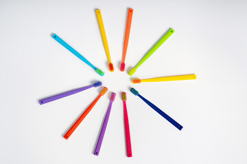 Naklejka premium Multicolored toothbrushes lie in a circle on a white isolated background, top view