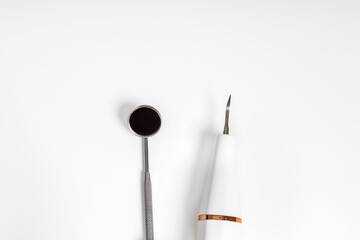 A dental mirror and a handpiece tool neatly placed on a white background, showcasing professional dental equipment.