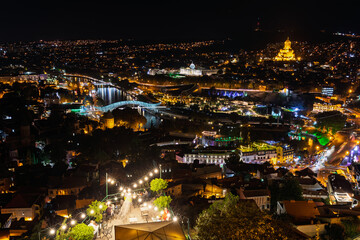 Fototapeta premium Panoramic Night View Of Tbilisi Cityscape With Peace Bridge And Sameba Cathedral