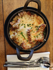 Delicious baked cheese dish served in a cast iron skillet, garnished with fresh chives, showcasing a mouthwatering culinary experience in a rustic setting