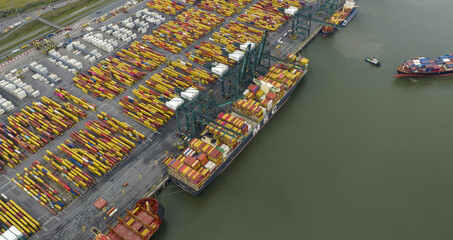 Aerial view of a bustling port where massive cargo ships meet rows of colorful shipping containers under the watchful eyes of towering cranes, Antwerp, Vlaanderen, Belgium.
