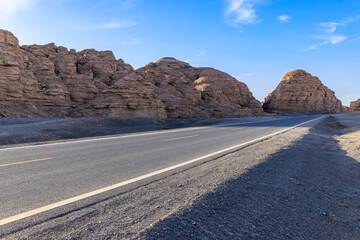 Empty asphalt highway road through the spectacular yardang landform and desert landscape in Xinjiang, China.