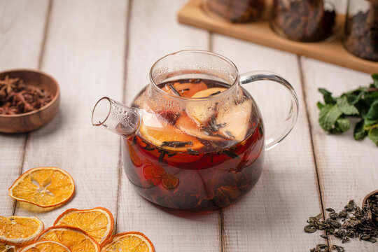 Aromatic Moroccan fruit tea brewed with citrus slices, spices and herbs served in a glass teapot on rustic table
