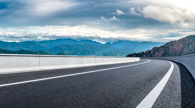 Empty asphalt road and green mountain natural landscape under cloudy sky - Powered by Adobe