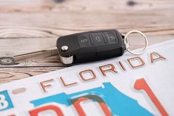 Remote control car keys on Florida license plate on wooden background. Concept of driving in...