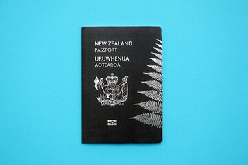 New Zealand black passport on light blue table background close up. Concept of travel and tourism