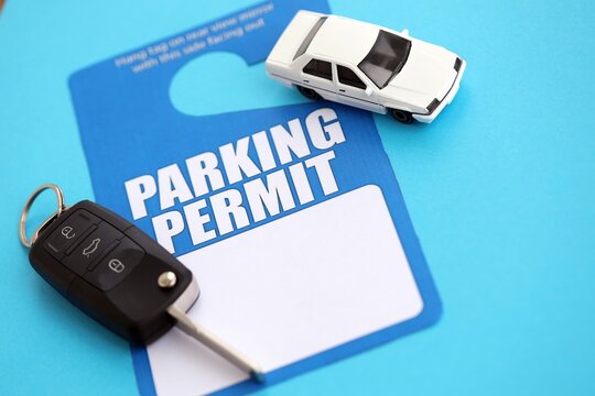 Parking permit paper notice tag for car interior with ignition keys and toy car. Parking permit for people with disabilities concept