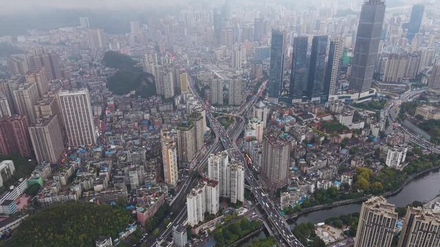 Revealing drone shot of a multi-tiered traffic interchange and highway flyover cutting through the dense cityscape of Guiyang, Guizhou Province.
