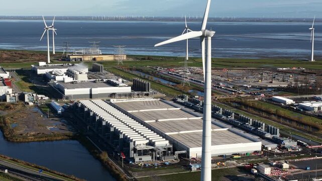 Aerial drone video of wind turbines powering a massive hyperscale data center, showcasing renewable energy sources for the huge consumption of modern IT infrastructure.