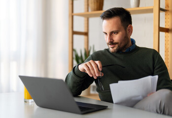 Man using smartphone and laptop computer for electronic banking, making reservation, online shopping