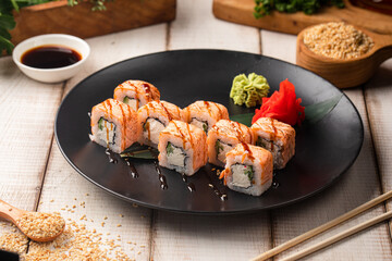 Philadelphia sushi rolls with creamy cheese, cucumber and seared salmon served on a black plate with wasabi