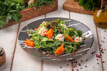 Vibrant pumpkin salad with mixed greens, seeds and creamy toppings served on a dark rustic plate