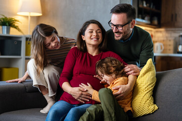 Happy family with pregnant mother and cute children have a fun at home and hug each other