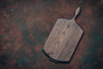 Empty wooden cutting board on dark rusty grunge background, culinary backdrop, top view, flat lay, copy space