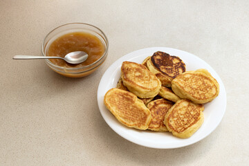 Fried pancakes on a white plate with a bowl of jam