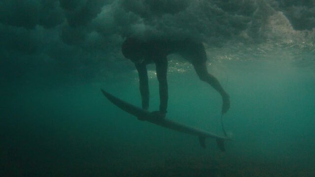 Underwater view of the surfer diving under the ocean wave in the Maldives