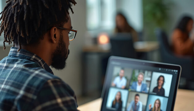 Black man attends virtual business meeting using laptop. Diverse colleagues gather remotely online. Digital conference call connects team. Distant workers collaborate via video chat in office space. - Powered by Adobe