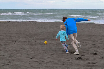 Two brothers play football and have fun on black sand beach in Kobuleti, Georgia