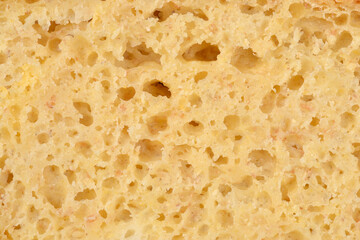 An extreme close-up of a slice of yellow cornbread, revealing its porous and slightly moist, spongy texture with a rough golden crust