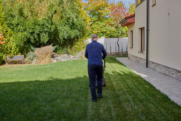 A middle-aged man takes care of the garden of his house, doing various maintenance tasks with the help of his wife.