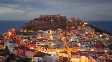 aerial shot historic fortress overlooking serene harbor and streets, dramatic sky over tranquil coastal town. Castelsardo. Italy