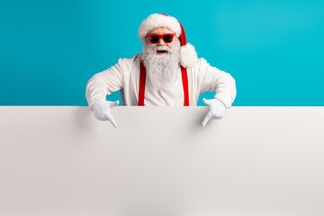 Santa with red suspenders beard holds blank sign against blue background creating festive humorous Christmas scene for holiday promotions
