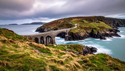 A stone bridge connects to a rocky, grassy island under a cloudy sky with blue water surrounding