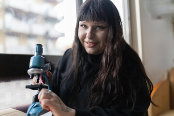 Young woman smiling holding toy microscope for learning