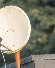 Satellite dish on a roof capturing signals with blurred trees in background