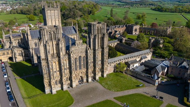 Aerial view of the majestic Wells Cathedral casting long shadows on the Cathedral Green, its intricate facade a contrast to the smooth lawn, Wells, England, United Kingdom.