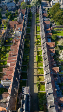 Aerial view of the ancient Vicar's Close, a symmetrical architectural marvel bathed in sunlight, showcasing the red rooftops against the green lawns, Wells, England, United Kingdom.
