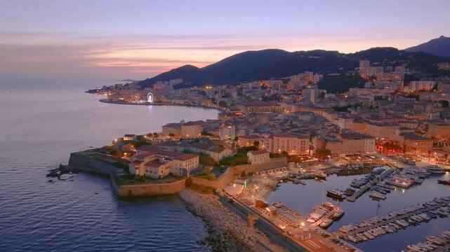 sunset over france coastal town with boats, scenic view of ancient castle and busy marina at dusk. Ajaccio