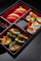 Japanese style bento box with nigiri and sushi on dark background isolated