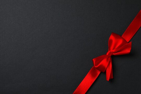 Stylish bow with red ribbon on black background, festive and elegant atmosphere
