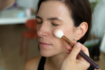 Woman using makeup brush during beauty process. Concept of cosmetic application and personal grooming in everyday life.