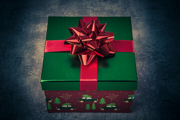 Christmas gift box with red bow on dark background. Toned.
