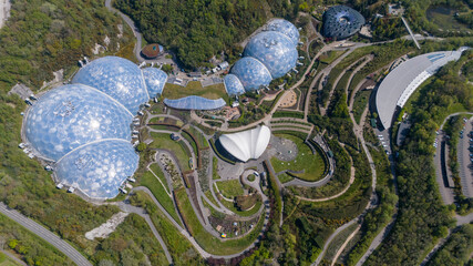 Aerial view of the Eden Project's distinctive biomes nestled within lush greenery, a vibrant tapestry of architectural marvels and natural beauty, Eden Project, Cornwall, United Kingdom.