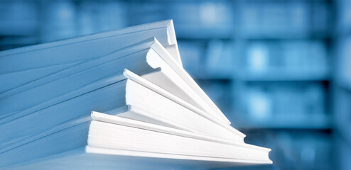Shallow and soft focus against macro view of stack of books with unfocused library background in blue color