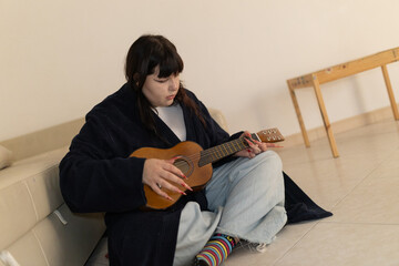Young woman playing guitar relaxing at home