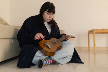 Young woman learning playing small string instrument at home