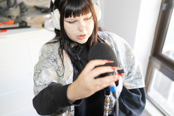 Young woman recording audio speaking into microphone