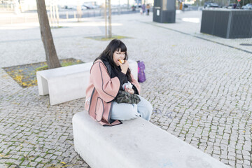 Young woman eating donut in urban environment