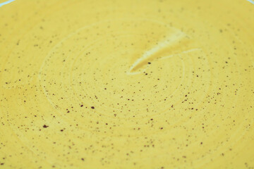 Close-up shot of enameled ceramic texture, yellow speckled plate