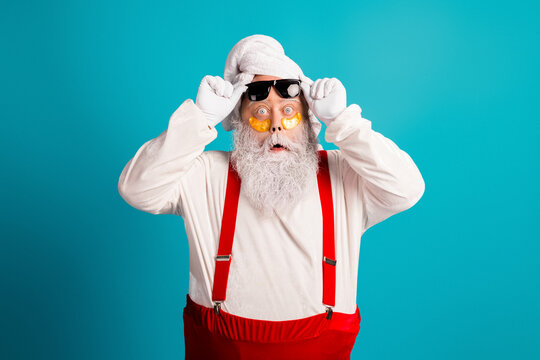 Santa costume grandpa with red suspenders and white beard poses funny and festive against blue background for christmas themed stock image