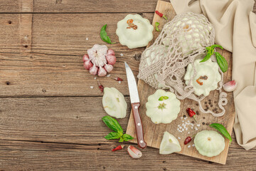 Pattypan squash, spices and herbs on a vintage wooden table with a crocheted handmade bag